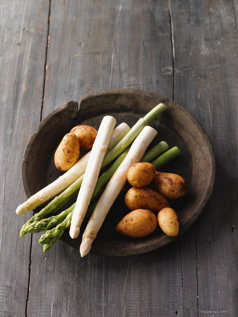 White and green asparagus with potatoes in a wooden bowl