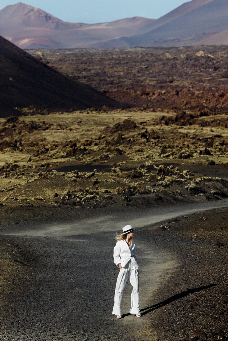 A blonde woman wearing a hat and a white linen suit