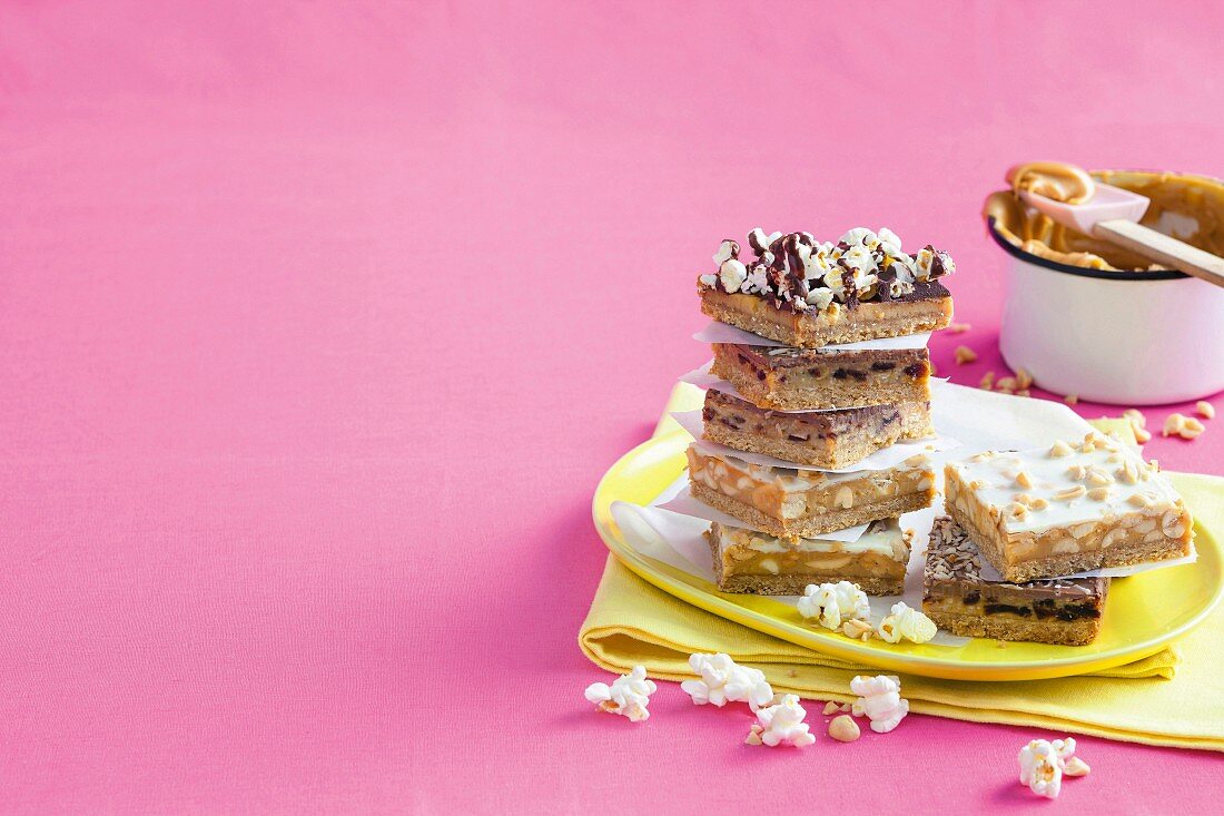 Salted caramel slices with popcorn and chocolate, with dates and coconut and with peanuts and white chocolate