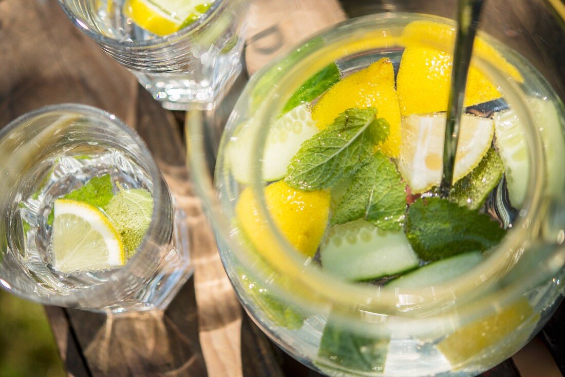 Lemon water with cucumber and mint on a wooden crate in the garden