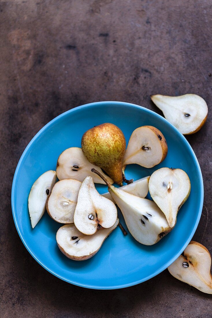 Fresh pears, whole and halved, in a blue bowl