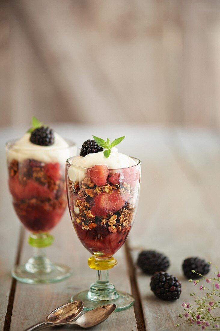 Layered blackberry and apple desserts with cereals and whipped cream