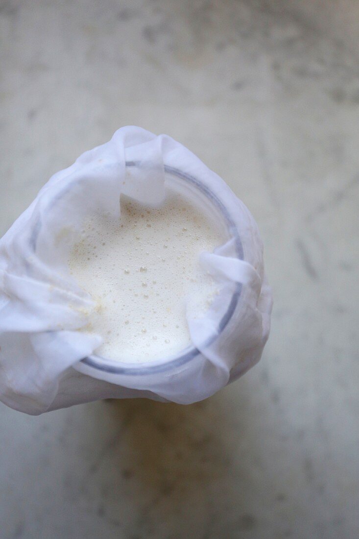 Homemade short-grain rich milk with a muslin cloth in a glass