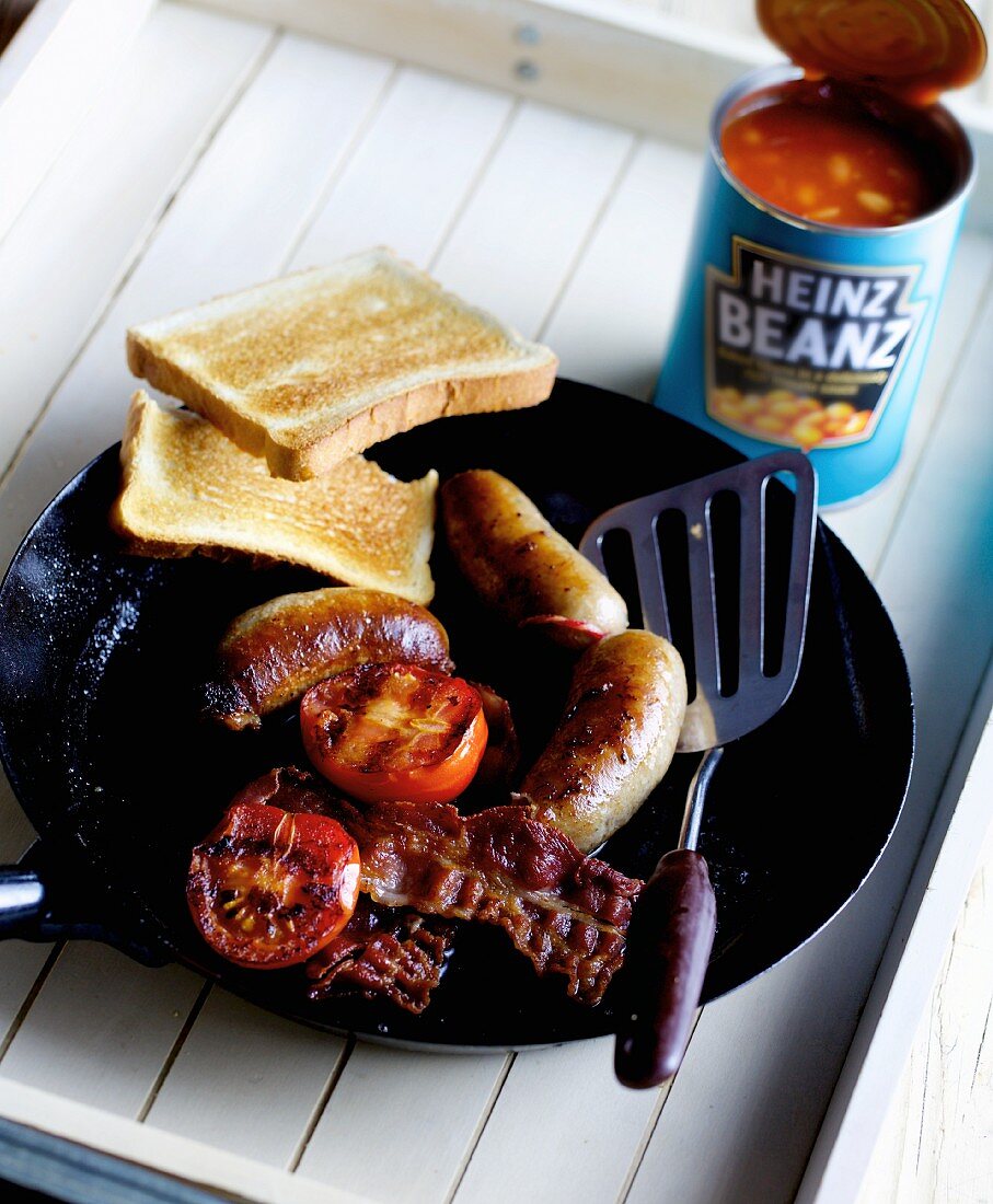 Hausgemachte Englische Bratwurst mit Grilltomaten, Bacon und Baked Beans