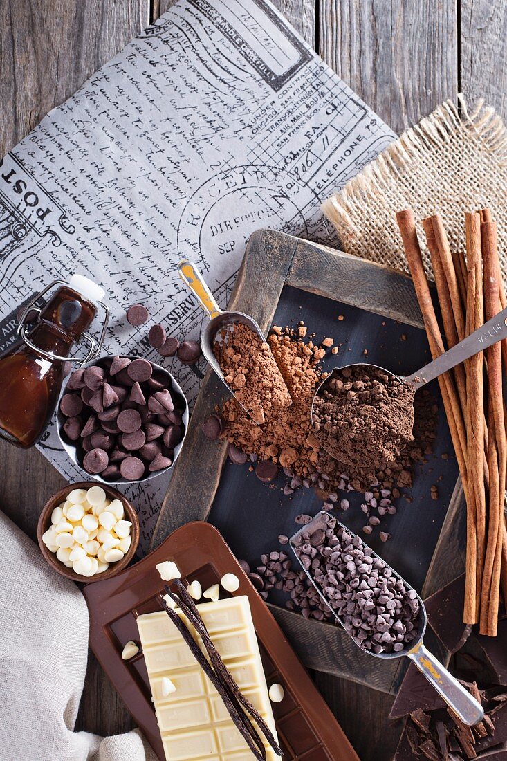 Schokoladenstilleben mit Chocolatechips, Kakao, Sirup, Vanilleschoten und Zimtstangen