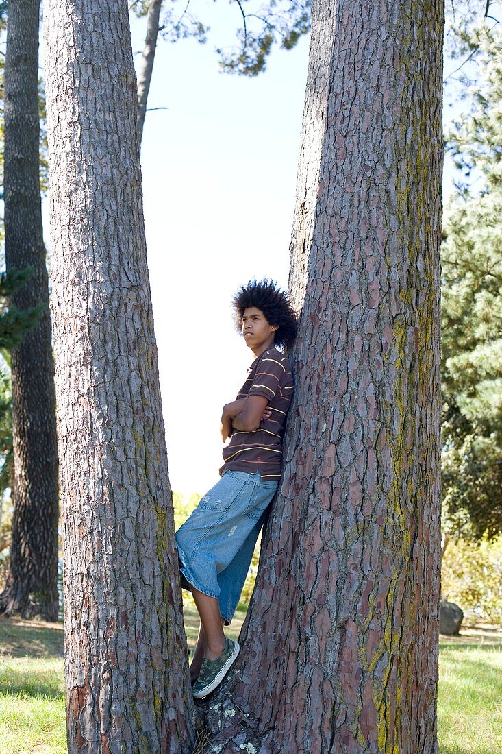 Teenager leaning against a tree