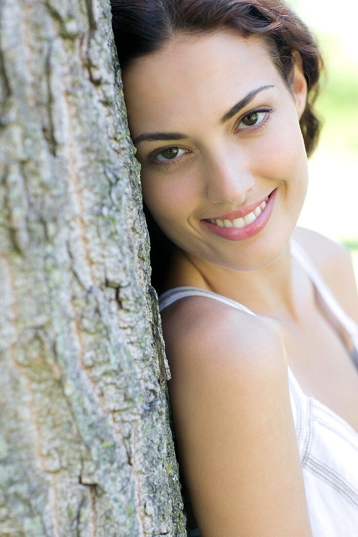Happy woman leaning against a tree
