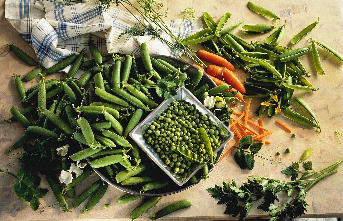 Peas, pea pods and carrots on tray and in bowl