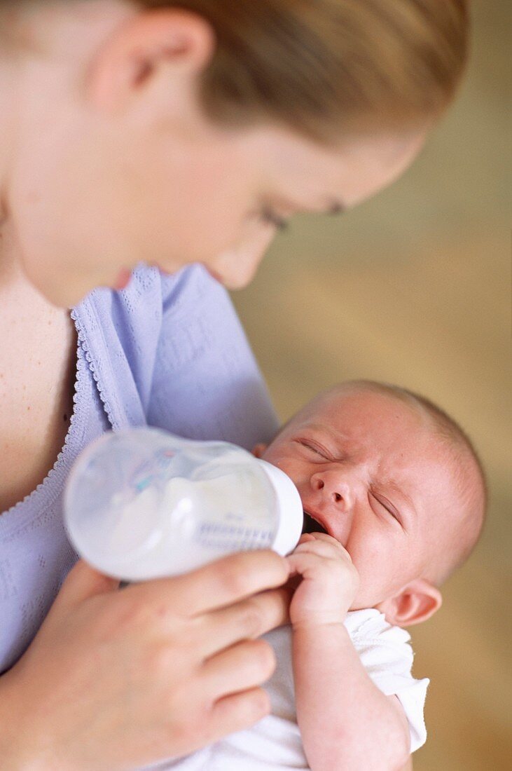 Mother bottle-feeding baby boy