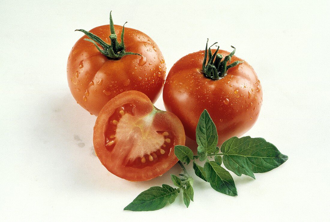 Zwei Tomaten mit Wassertropfen & eine halbierte Tomate