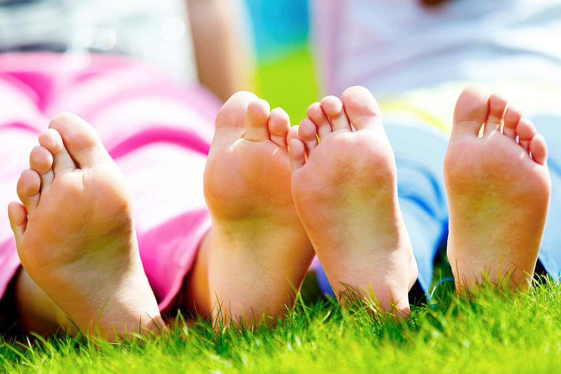 Children sitting on grass with bare feet