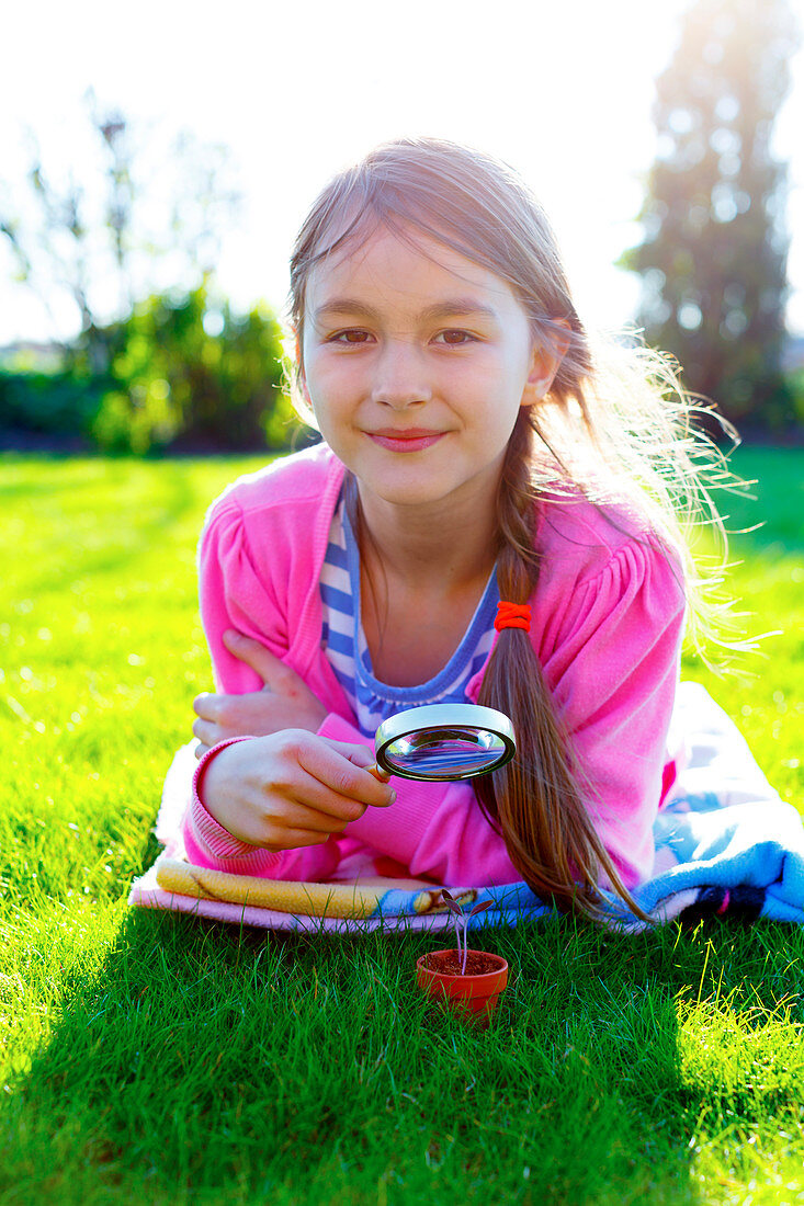 Girl with a magnifying glass and seedling