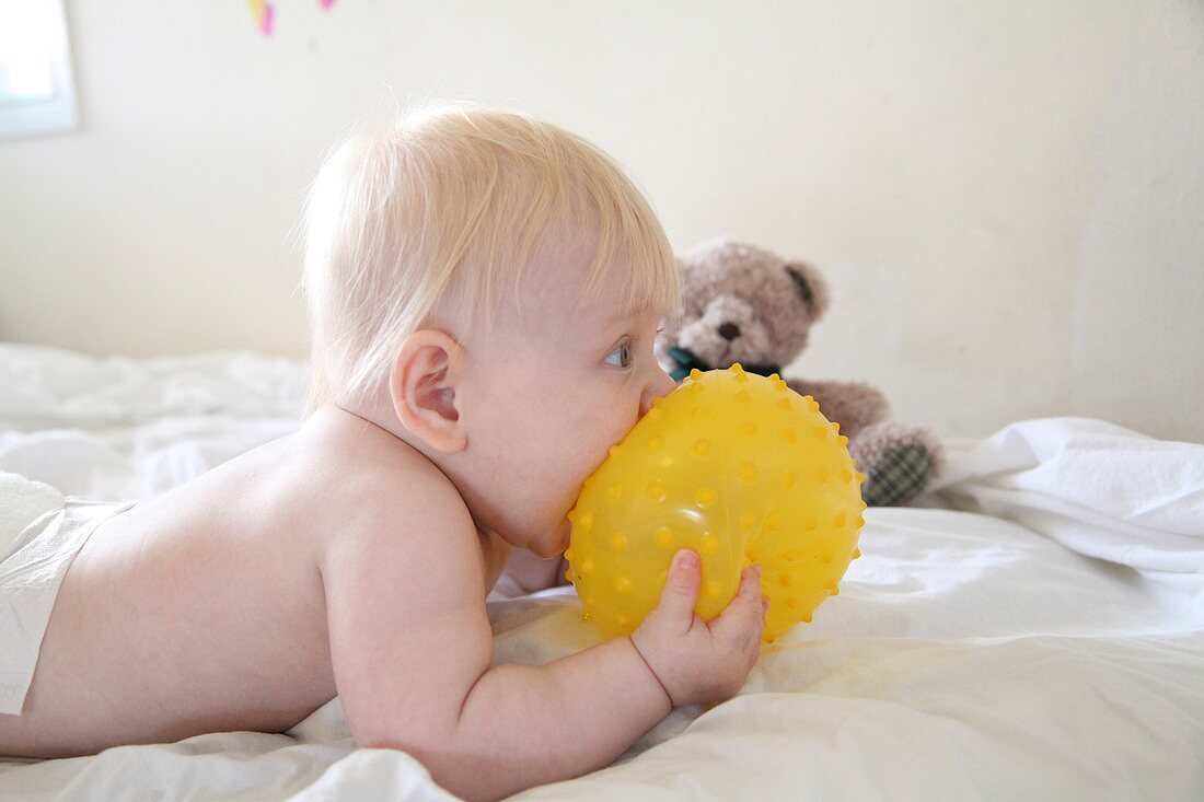 Baby eating a yellow ball