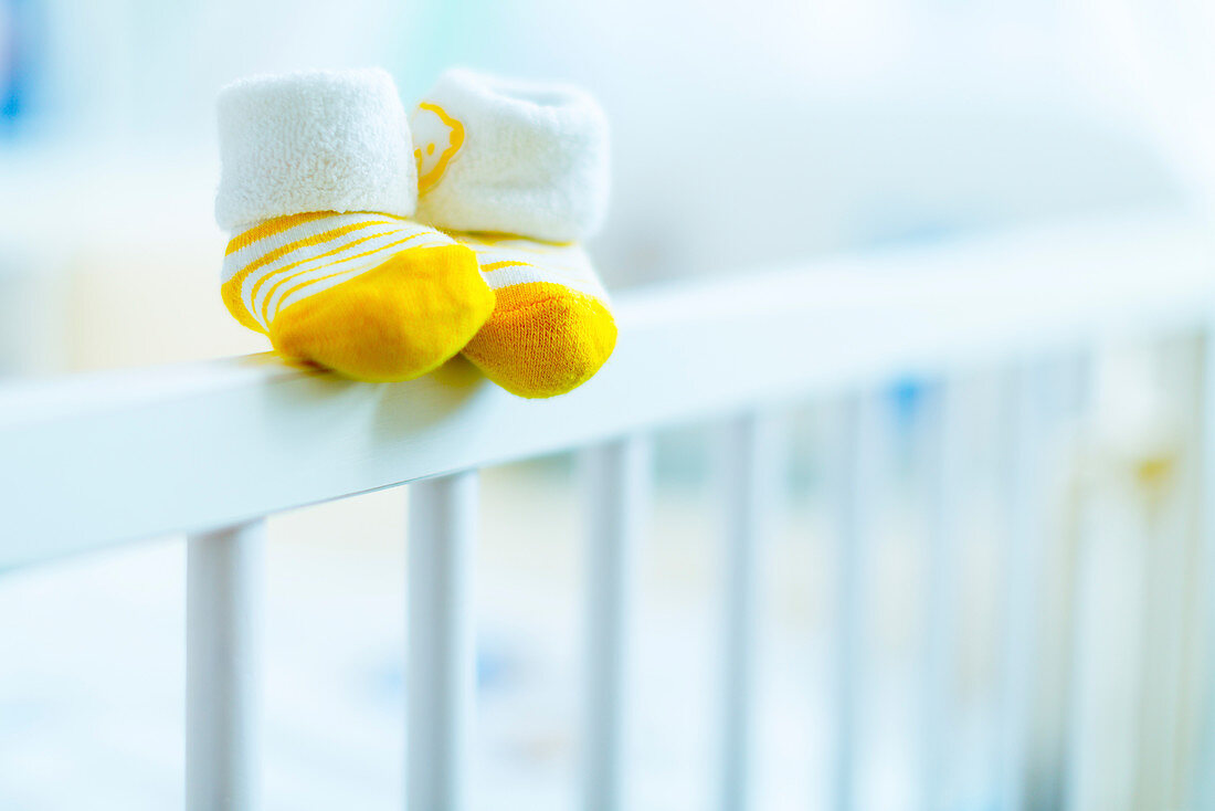 Baby shoes on the edge of a cot