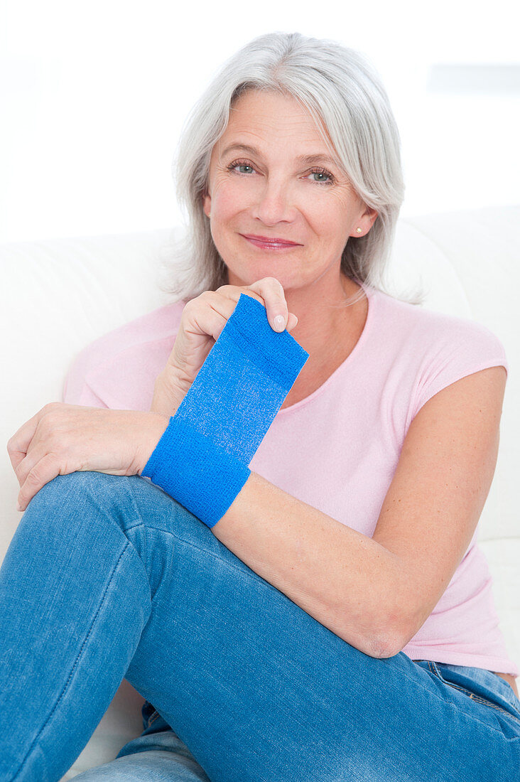 Woman putting bandage on wrist