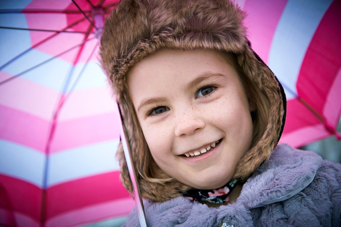 Young girl wearing furry hat with umbrell