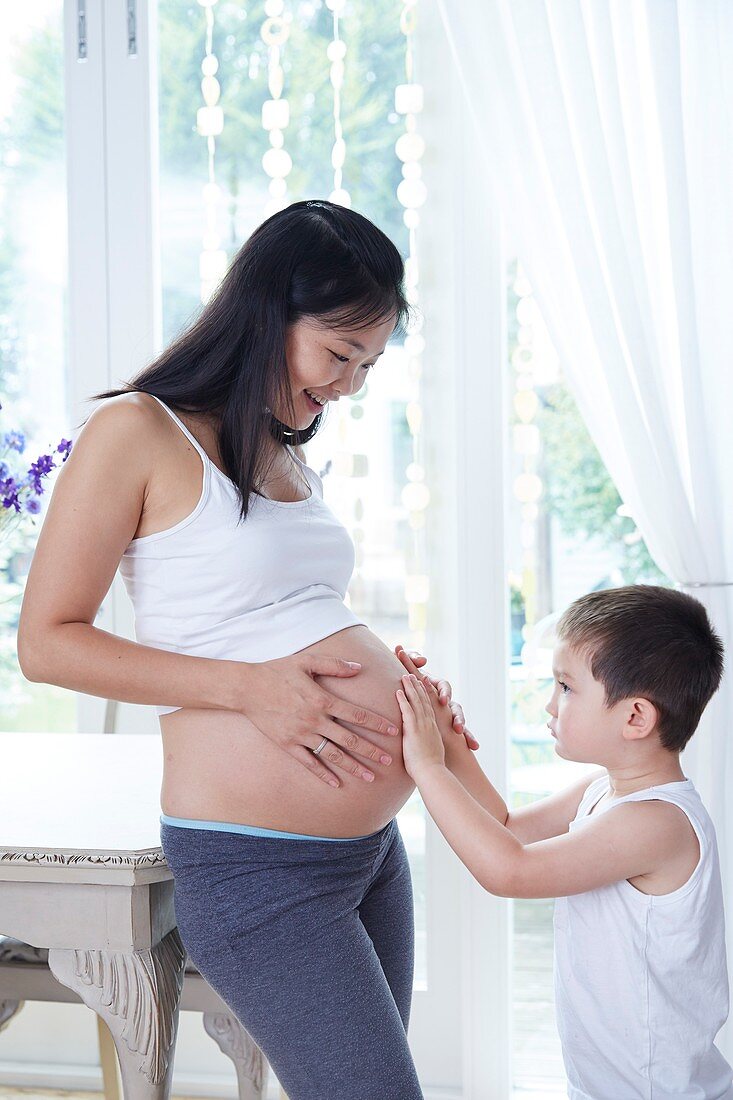 Pregnant woman with son touching tummy