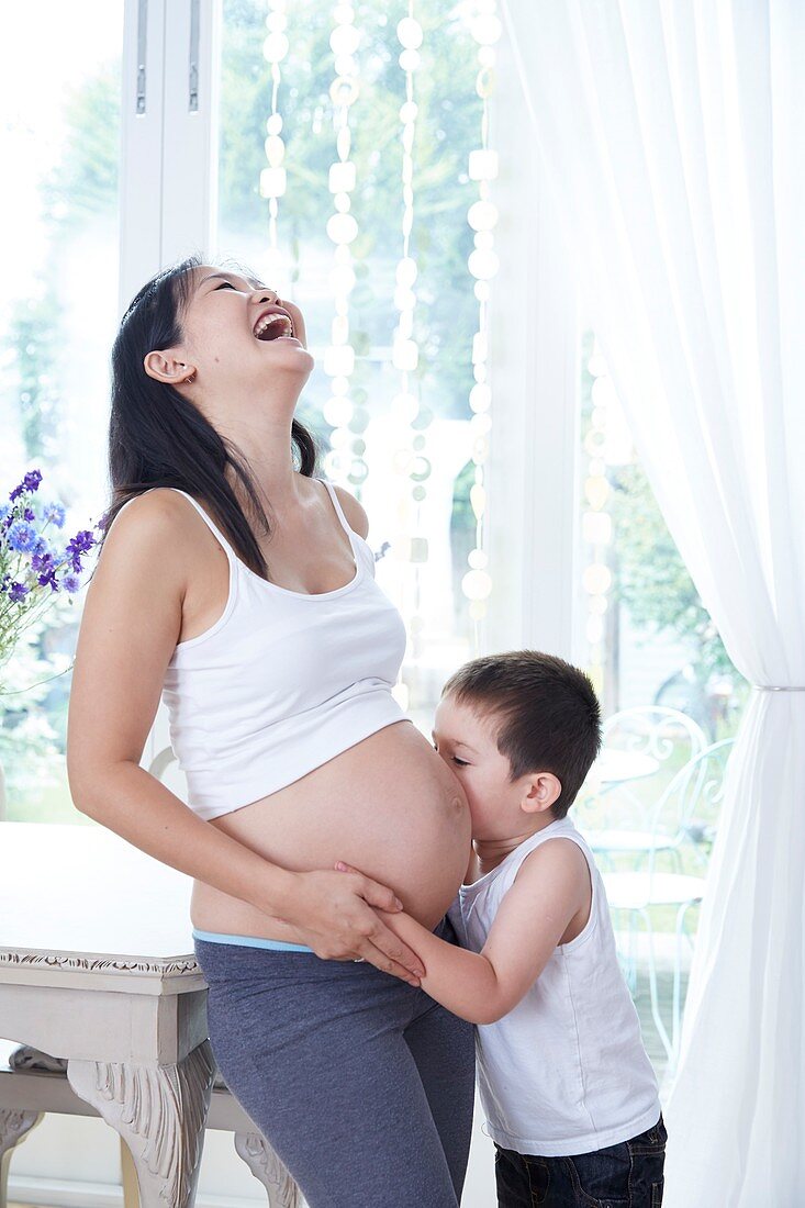 Pregnant woman laughing with son kissing