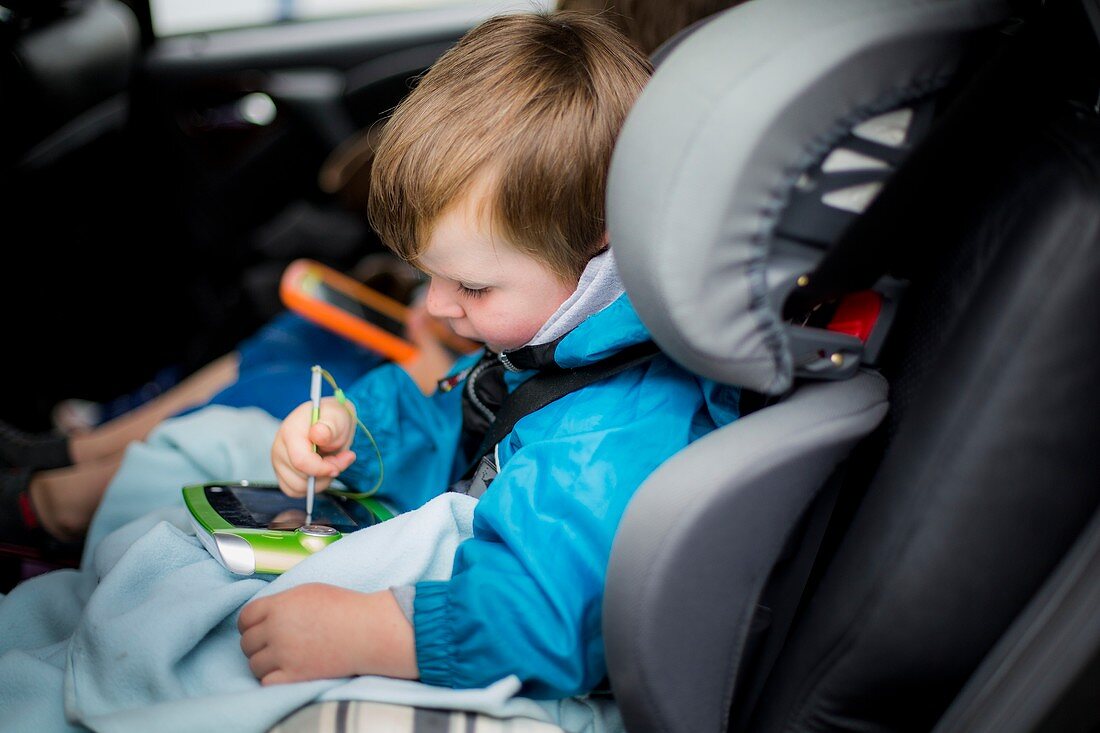 Boy in car using digital device