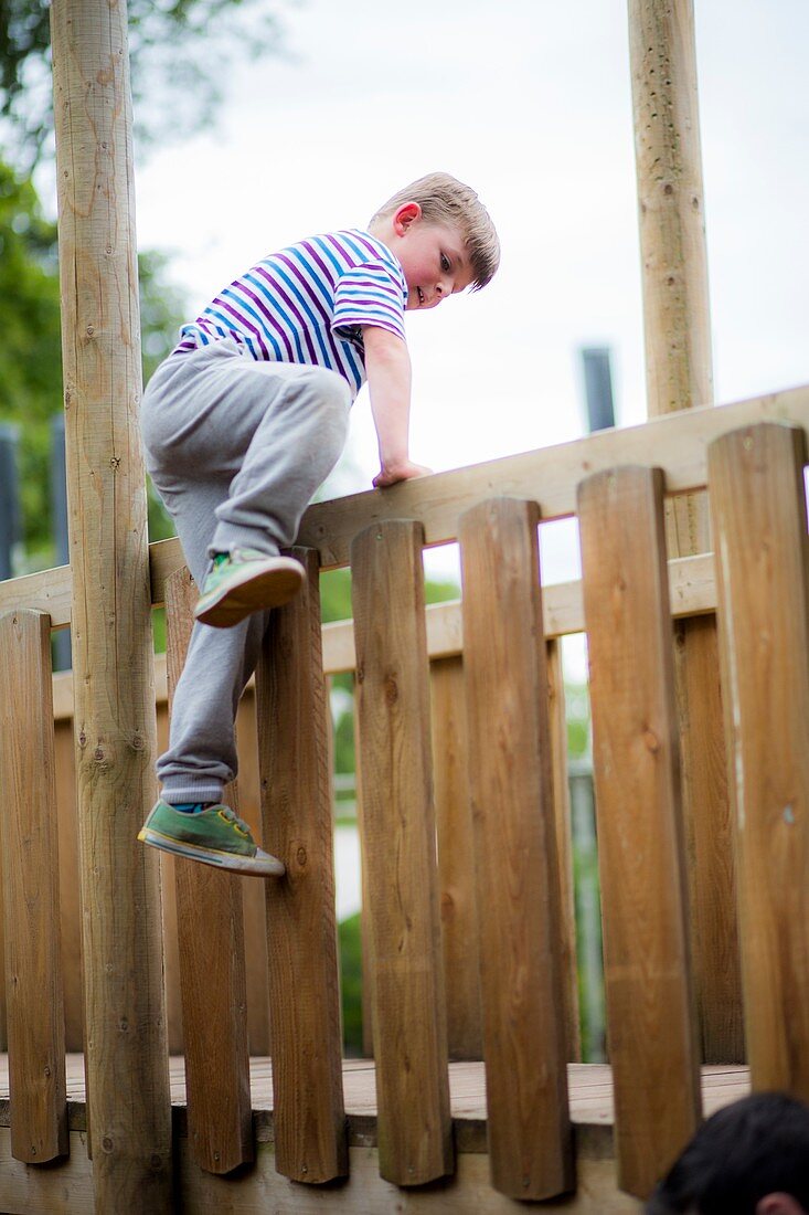 Boy climbing over wooden fence