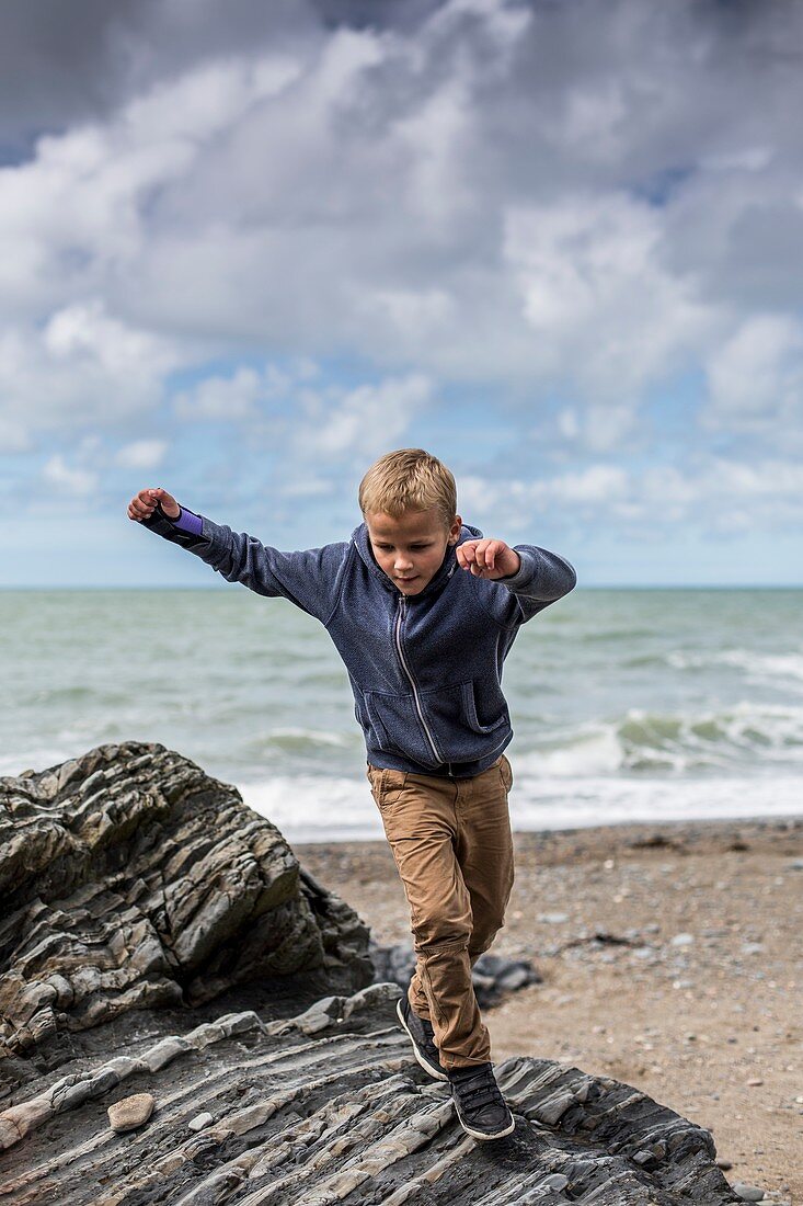Young boy playing on rocks on beach