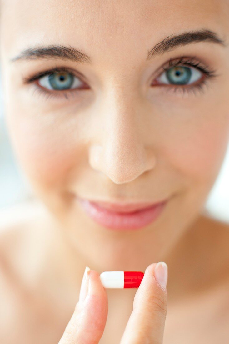 Woman holding a red and white capsule