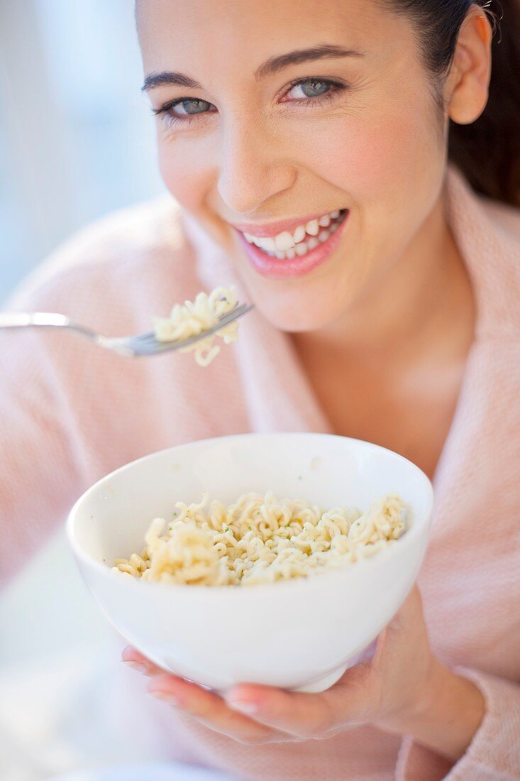 Woman eating bowl of noodles