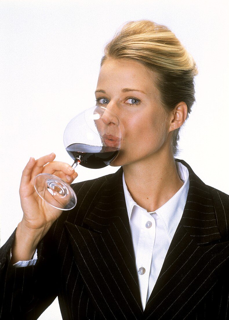 Junge Frau trinkt Rotwein aus Stielglas