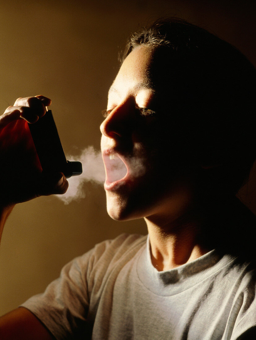 Young woman using aerosol inhaler for asthma