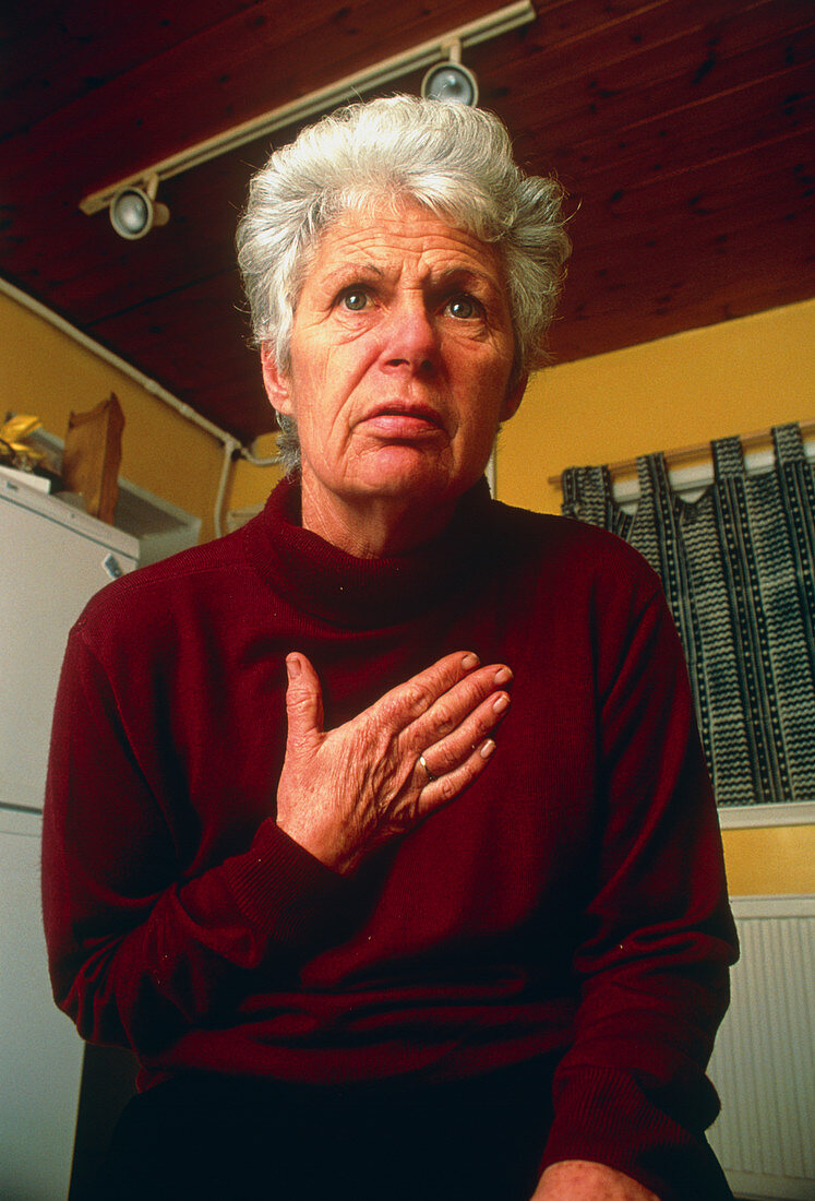 Elderly woman holding her chest in angina attack