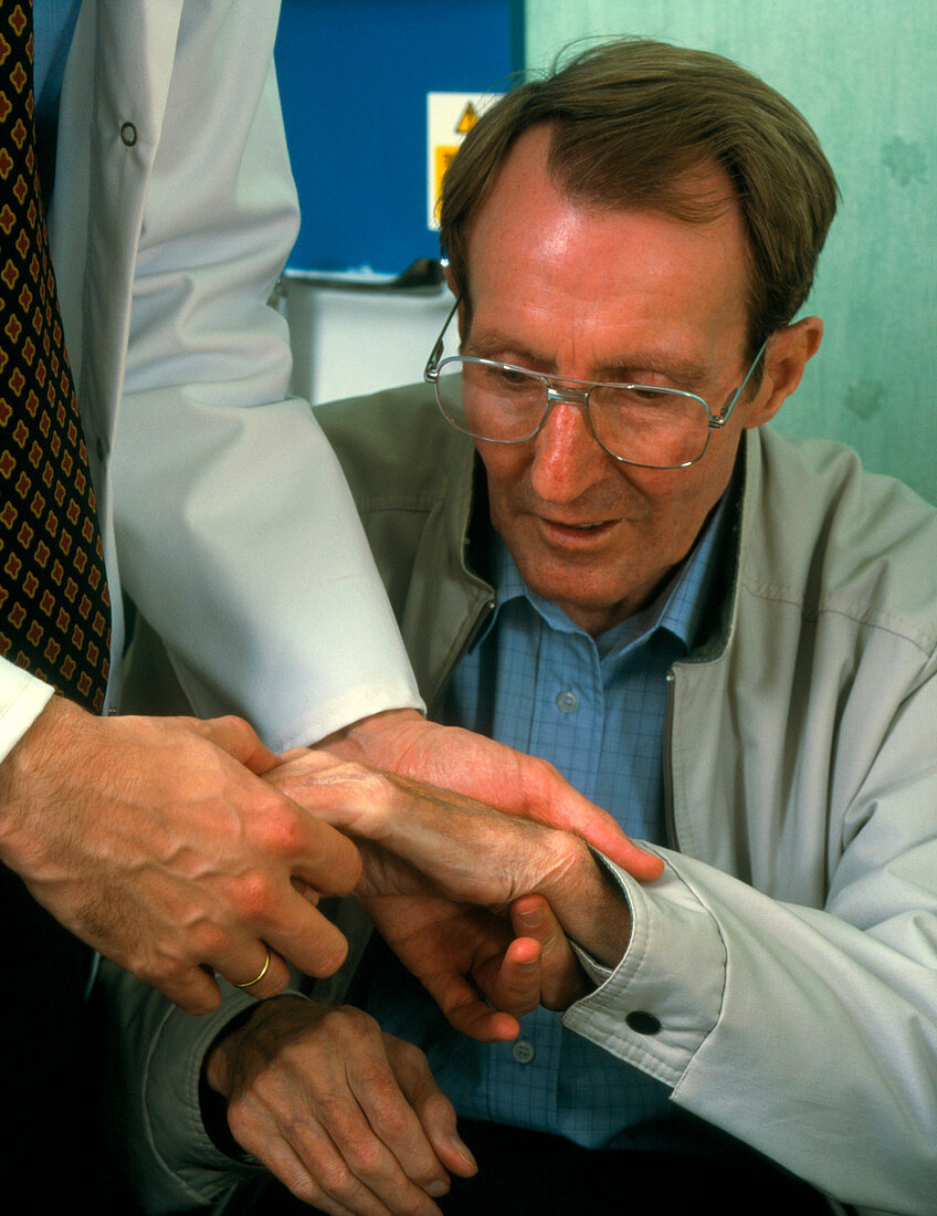 Hand examination of man with Parkinson's disease