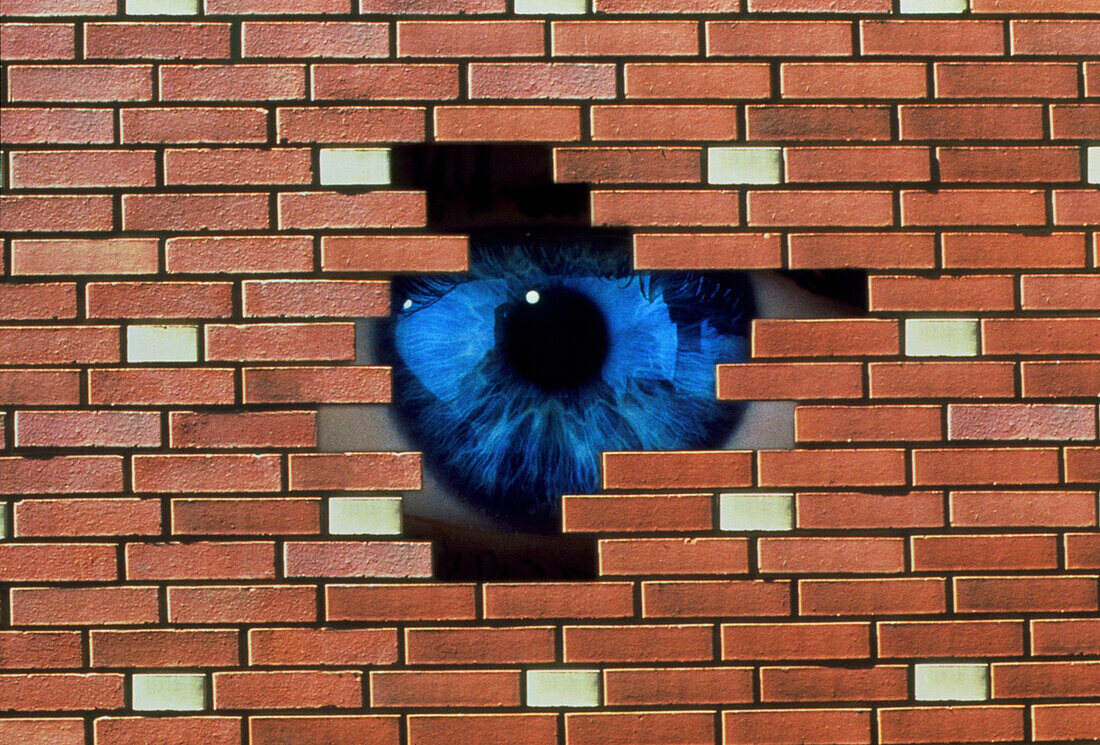Abstract of eye looking through hole in brick wall