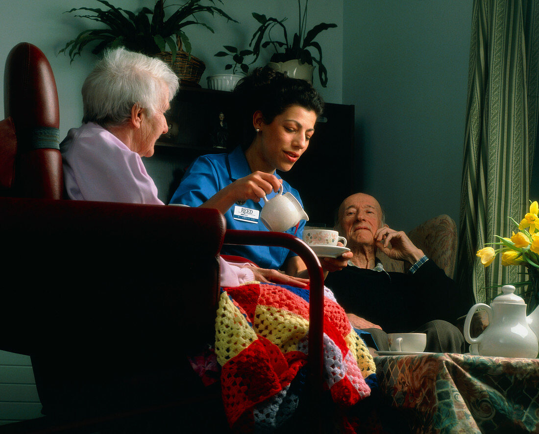 Nurse pouring tea for elderly people at home
