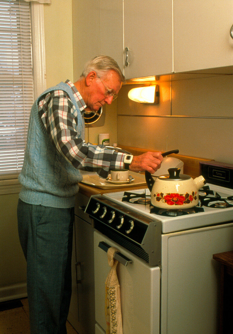 Elderly man cooks while wearing emergency device