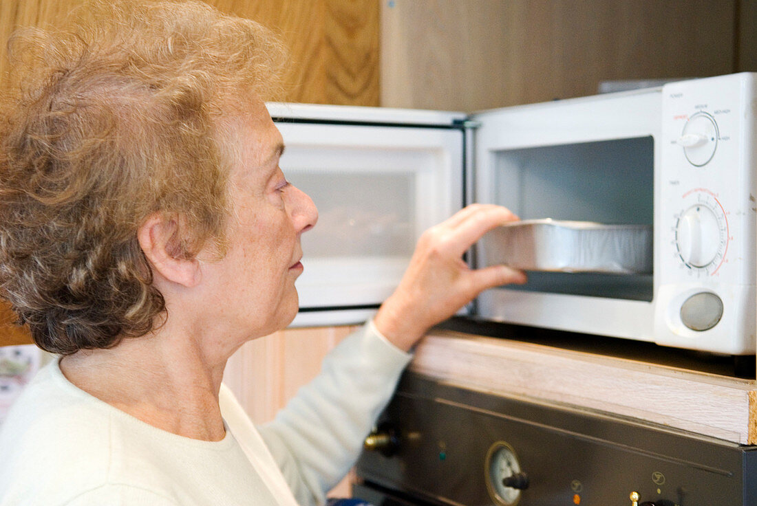 Elderly woman using a microwave oven