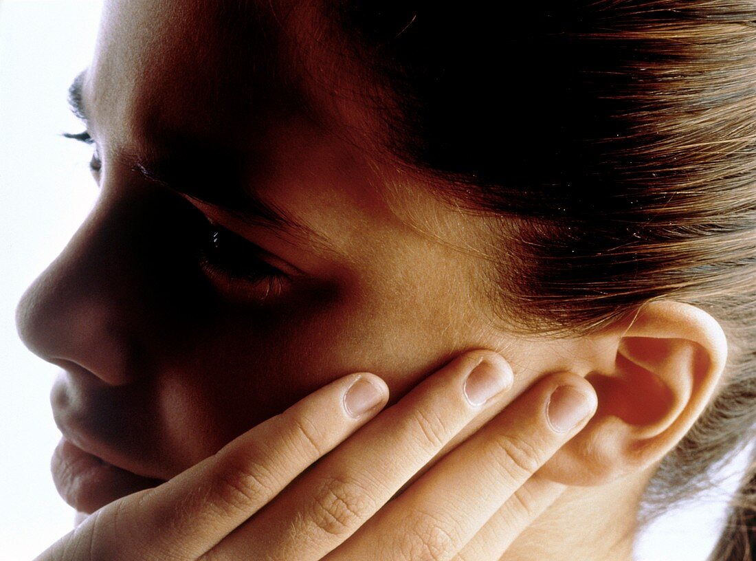 Girl holds the side of her mouth suffering pain