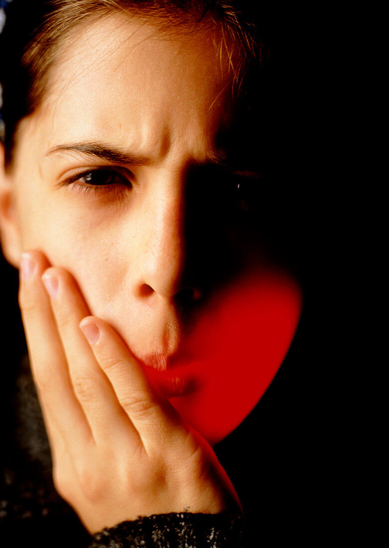 Girl holds the side of her mouth suffering pain