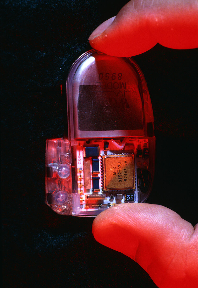 Fingers hold a heart pacemaker for implantation