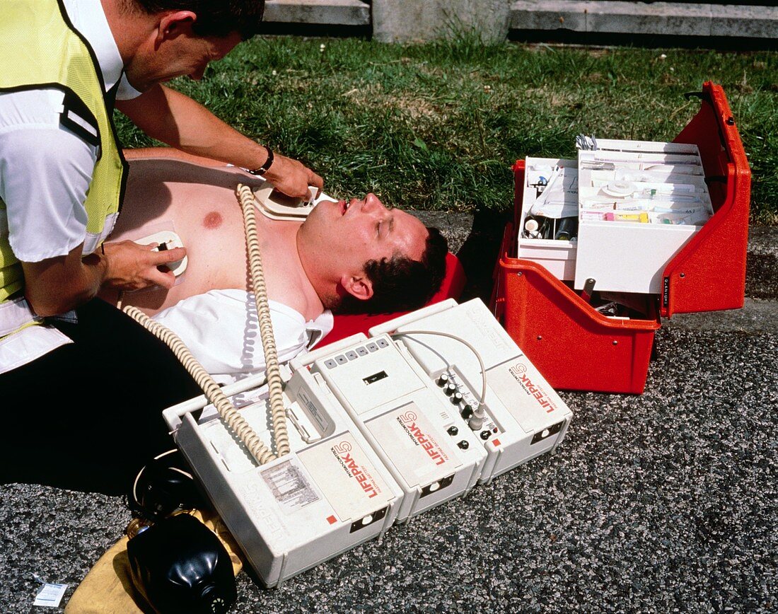 Ambulanceman using portable defibrillator machine