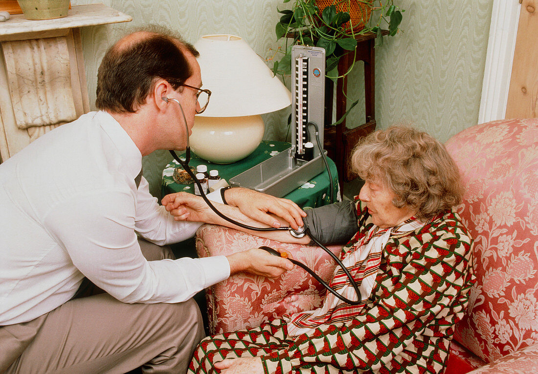 GP taking blood pressure of patient at home visit