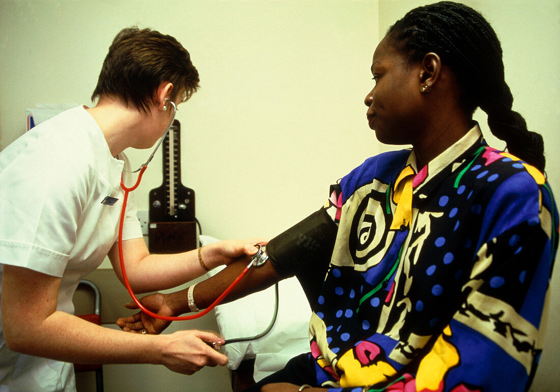 Nurse taking blood pressure of a female patient