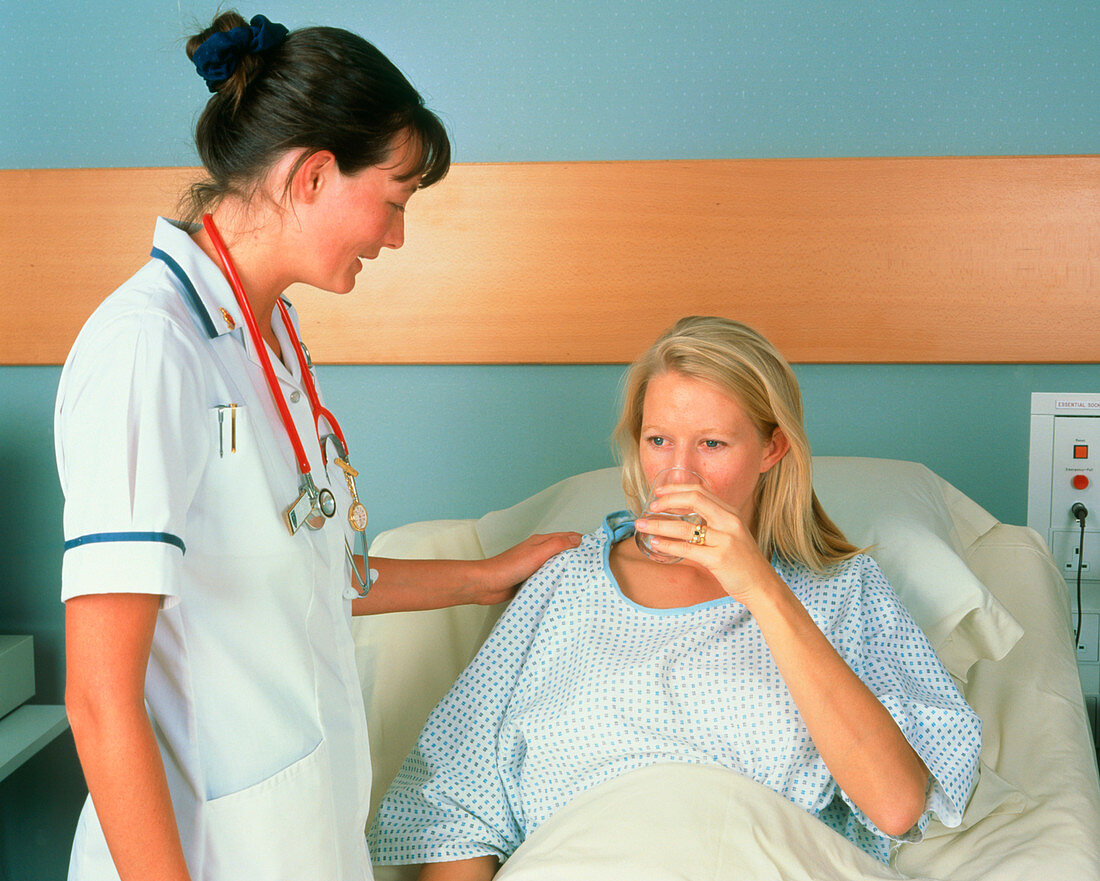 Nurse comforting female patient in private room