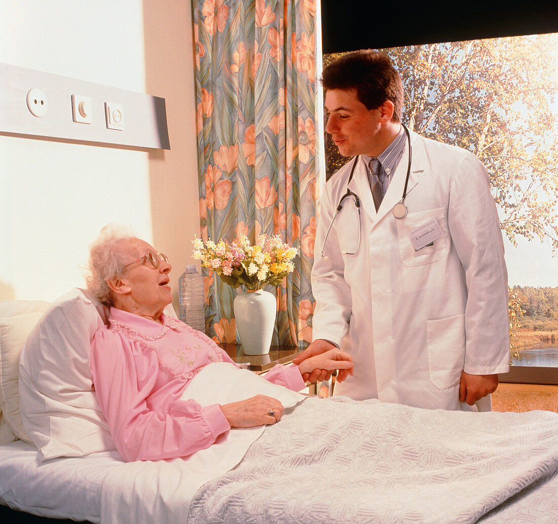 Doctor talking to elderly woman in hospital bed
