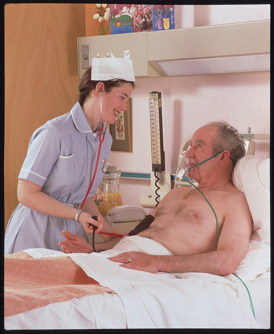 Nurse takes blood pressure of elderly man in ward