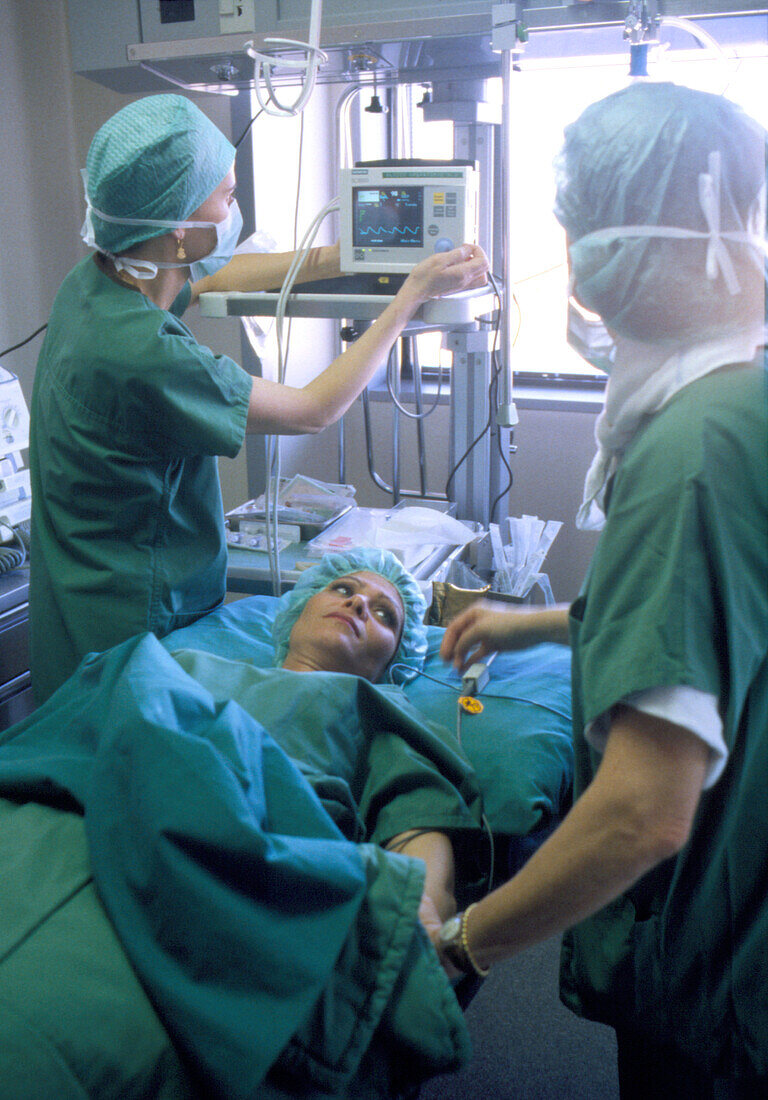 Medical staff monitor a woman after breast surgery