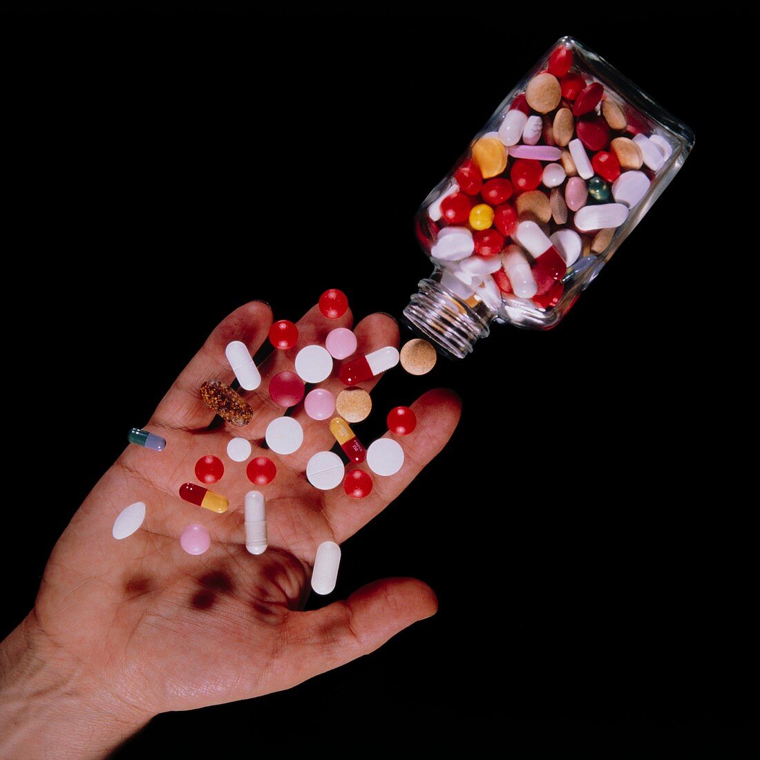 Bottle of assorted pills tipped into a hand