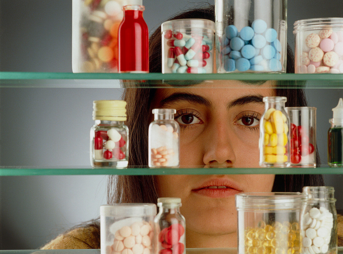 Young woman looks through a medicine cabinet