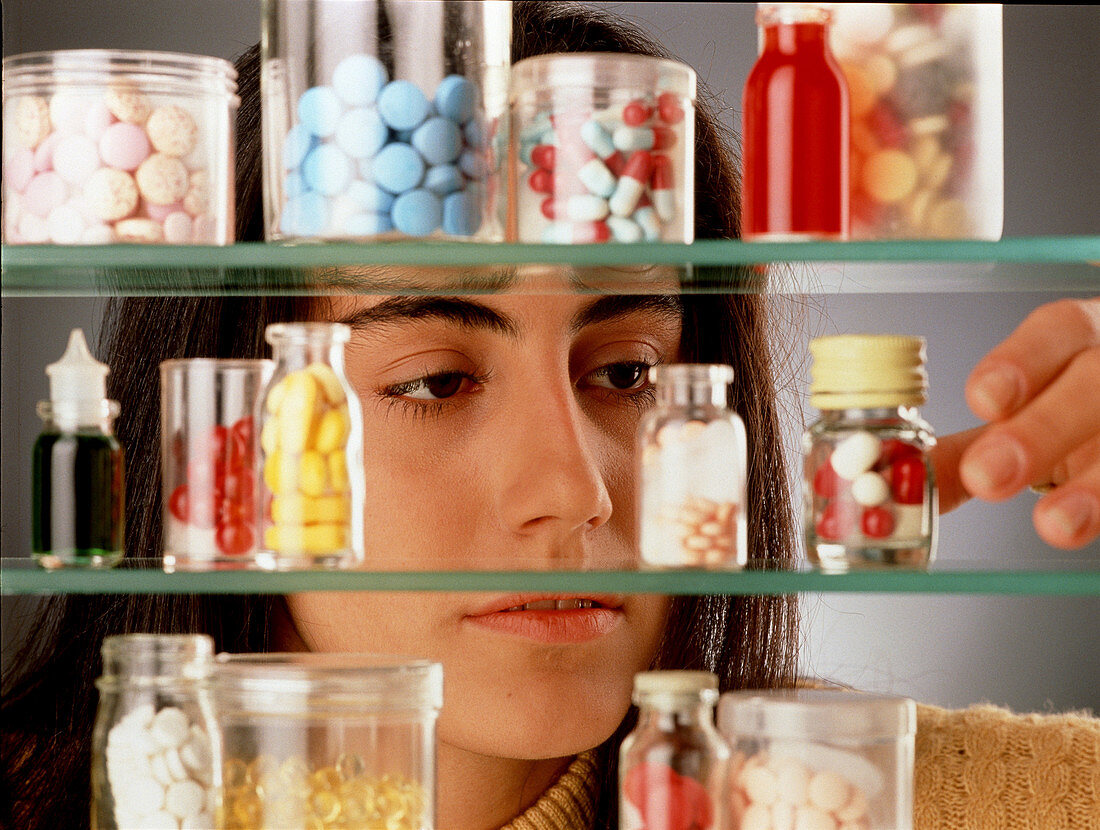 Young woman takes pills from a medicine cabinet