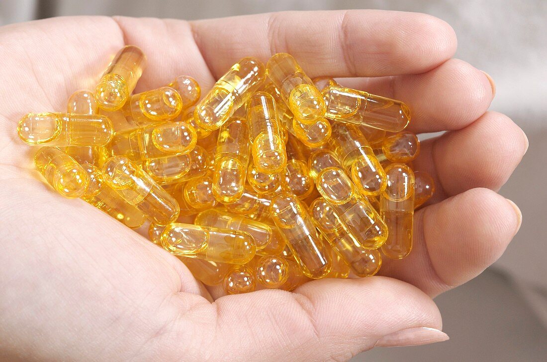 Woman holding a handful of oil supplements