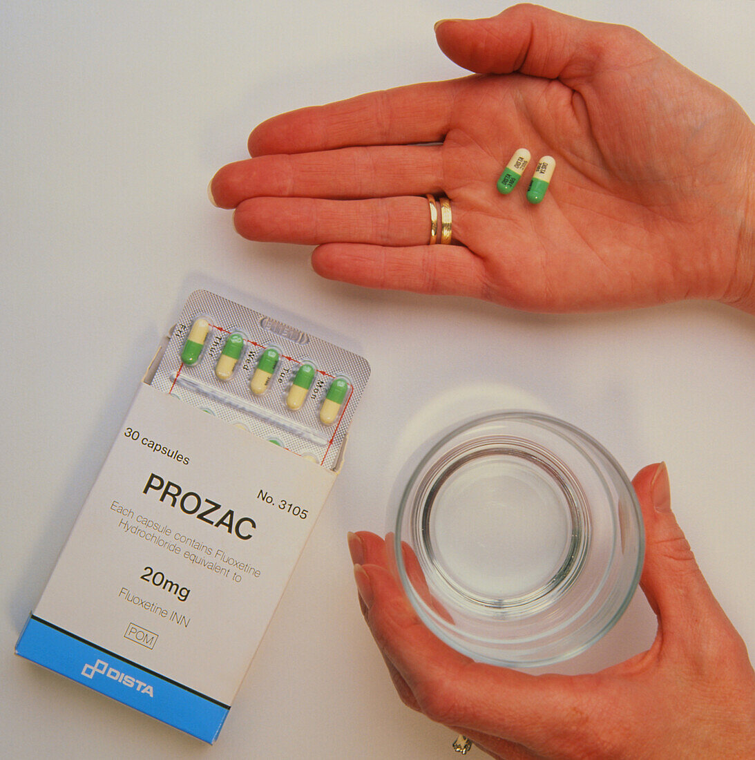 Prozac pack with pills in hand and glass of water